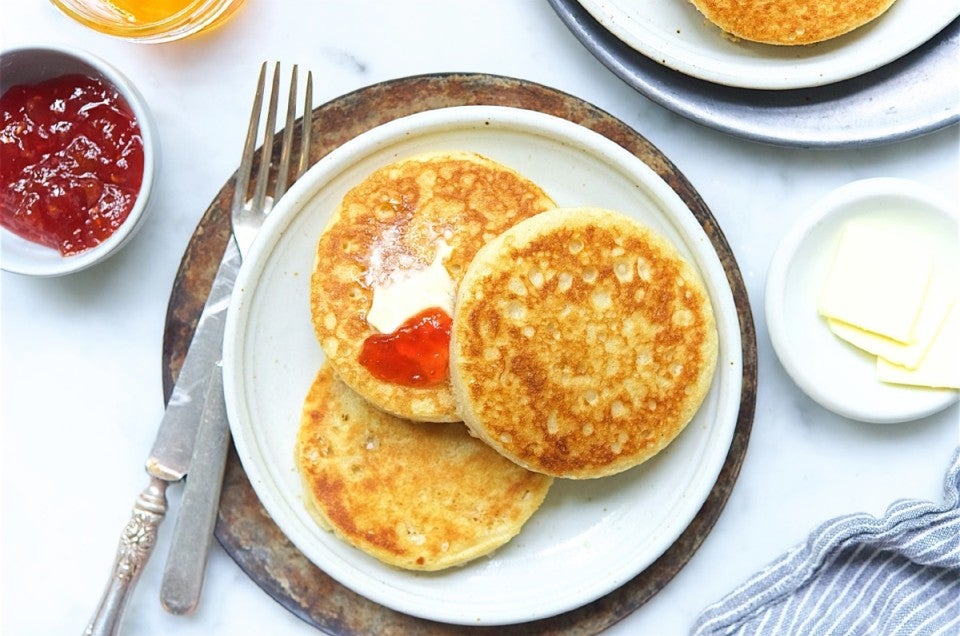 Three buttered sourdough crumpets on a plate.